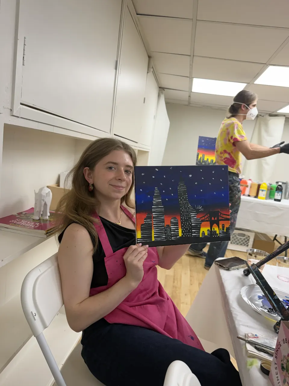 A smiling guest holding her colorful finished cityscape