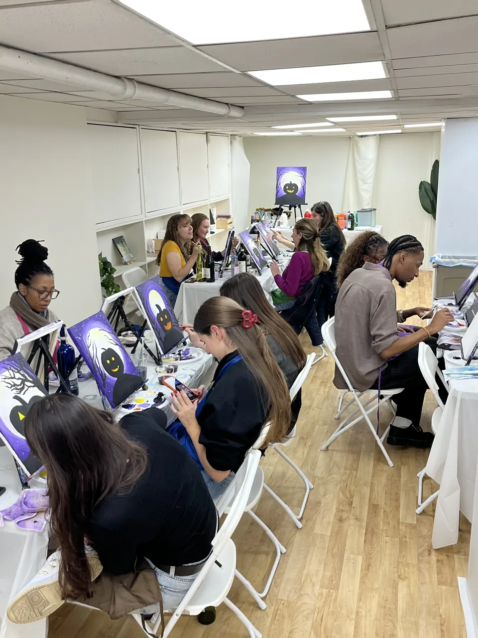 Guests painting together around the long studio tables