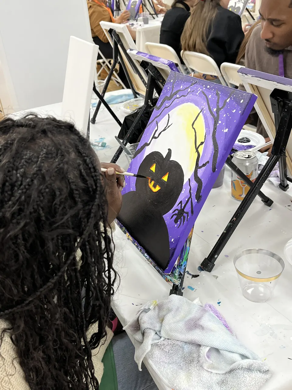 A guest adding details to a purple Halloween painting