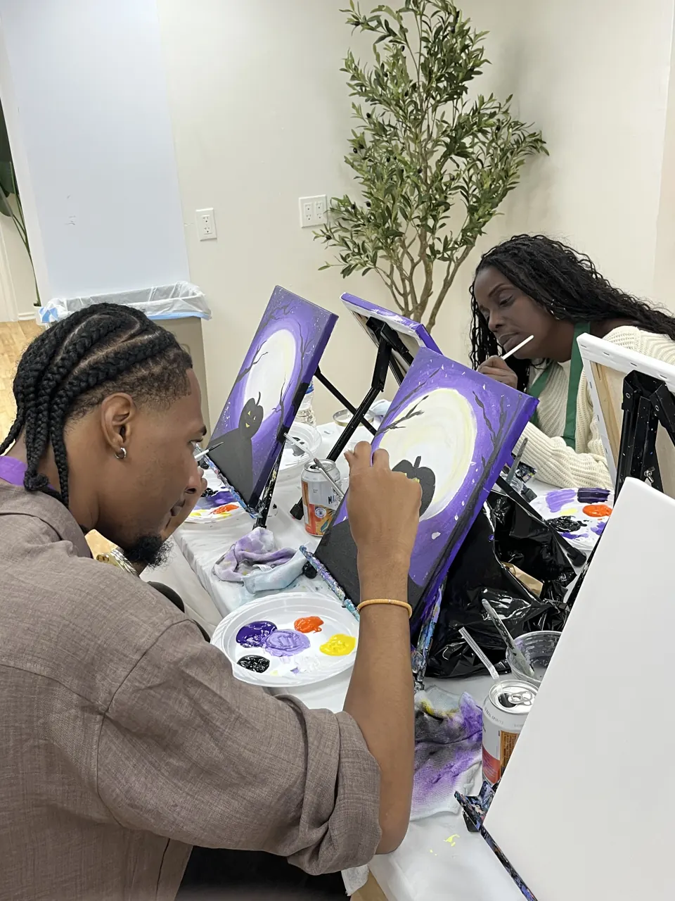 Two guests painting Halloween canvases together at the studio